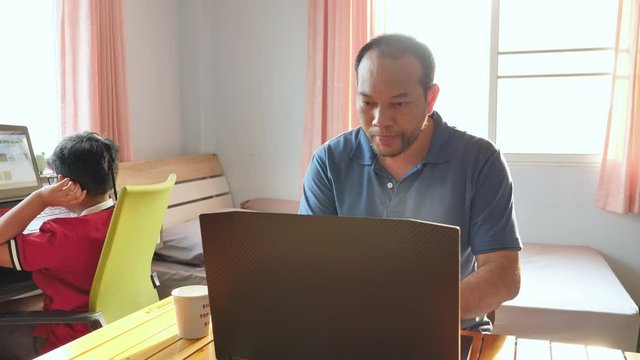 Asian Father Working From Home Using Laptop And Drink Coffee In The Bedroom With My Son In The Evening Sun The Sunlight Sent From The Window.