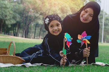 Happy Asian Muslim mother and daughter enjoy spending time together in a park, Muslim mother and daughter concept