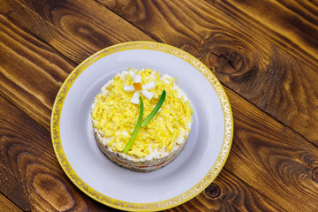 Traditional russian layered salad Mimosa with spring decoration Daffodil. Decoration is made of egg, green onion and carrot. Top view