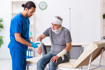 Fototapeta premium Young male doctor and old patient in first aid concept