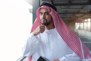 Modern Arabic businessman in tradition suit looking at camera, Saudi Arab Man thinking