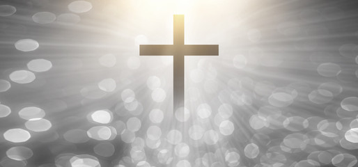 The Christian cross looks bright in soft white and the glittering bokeh background is the light of...