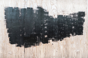 Black paint strokes on pieces of plywood wall, urban grunge style