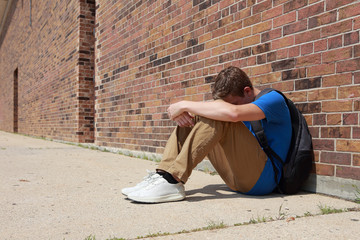 Depressed upset teenage student sitting outside school