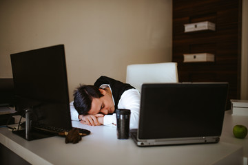 Young caucasian businessman is sleeping on a desk in front of a computer. Tired business man in office