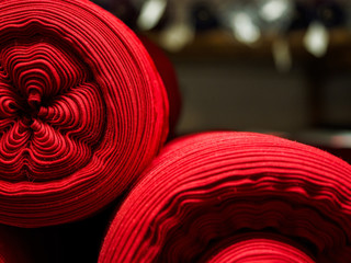 Several red rolls of knitted fabric. Woven factory or warehouse - obrazy, fototapety, plakaty