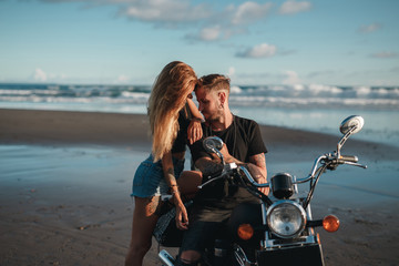 Young beautiful couple hipsters in stylish clothing for a retro motorcycle on the street, outdoor...