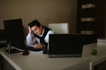 
Young caucasian businessman in the office working on computer. Businessman, work and technology