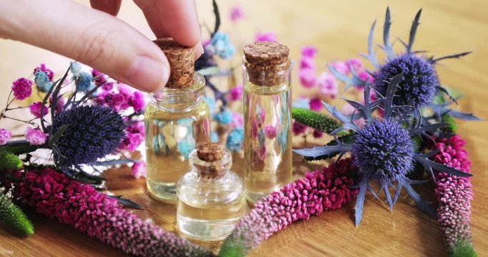Perfumer creating making new aroma liquid parfume taking essential oil from vial using pipette. Glass bottles among fresh flowers. Professional production of homemade perfume, scent, fragrance.