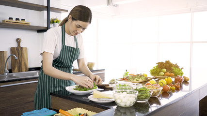 Asian women interested in good health.Mixing vegetable salad.Concept of happy family, modern kitchen,