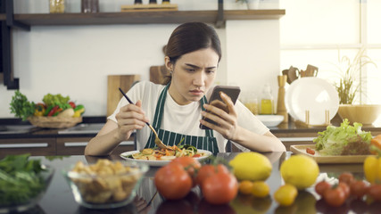 Asian Women Eating Salad While Sitting in Modern Kitchen.And looking at the news with a serious expression.While in the house to be detained during an epidemic Coronavirus(Covid-19).