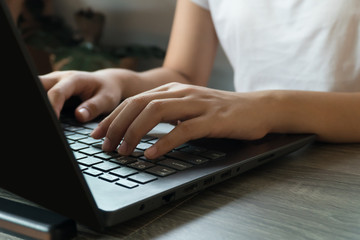 Young business woman sitting at table with laptop and taking notes in notebook.