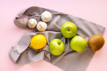 Fruits and vegetables with reusable fabric bag on a pink background