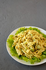 Homemade Coronation Chicken Salad on a white plate on a gray background, low angle view. Space for text.