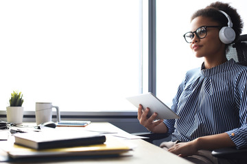 Beautiful business woman is working using digital tablet while sitting in creative office