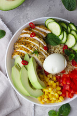 Buddha bowl with soft boiled egg, avocado, grilled chicken, cucumber, bell pepper, corn and bulgur. Concept for clean and balanced healthy food. Top view.
