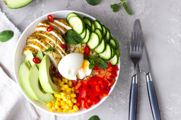 Buddha bowl with soft boiled egg, avocado, grilled chicken, cucumber, bell pepper, corn and bulgur. Concept for clean and balanced healthy food. Top view.