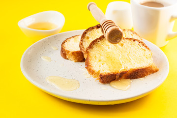 Sandwich with honey on a plate. Yellow paper background. Idea for breakfast or snack.