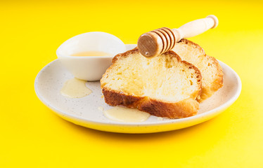 Sandwich with honey on a plate. Yellow paper background. Idea for breakfast or snack.