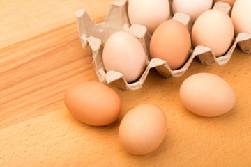 brown chicken eggs in an open cardboard box with eggs on a wooden table. Natural healthy food.