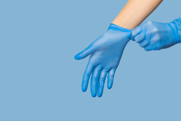 The doctor puts on sterile gloves on a blue background. Infection control concept. Danger of spread of infection