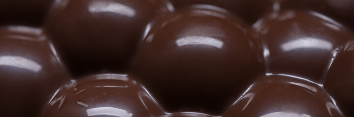 Close-up of porous bar of chocolate. Macro shot of dark sweets. Coffee beans and bubbles texture. Calories and antioxidant. Yummy and delicious dessert concept