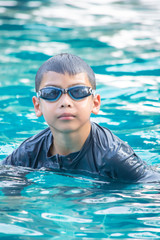 Portrait Asian boy wearing swimming goggles in the pool.