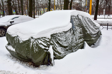 old car covered with case and white snow