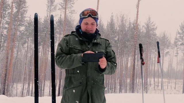 travel concept - tourist takes picture of two pairs of wide skis in village in winter day on smartphone, Russia