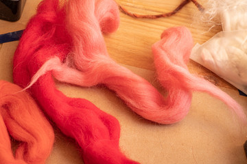Background with wool for felting red color lying on a wooden table