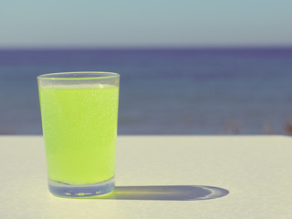 Citrus drink in glass on sea shore