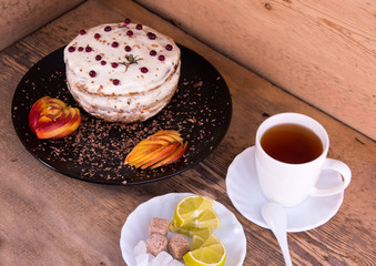 Obraz na płótnie Canvas Cake on a black plate, apple closeup, tea mug, plate with lemon, sahora, wooden background