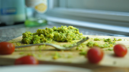 Close up of mashed avocado on a wooden board for guacamole ar bruschetta