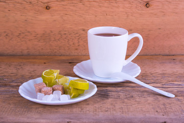 Mug of tea, plate with lime, sahora, on wooden background
