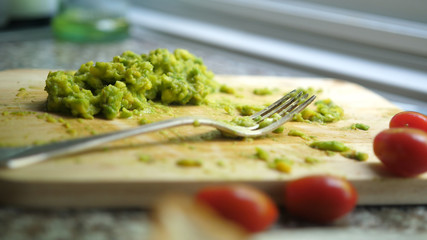 Close up of mashed avocado on a wooden board for guacamole ar bruschetta