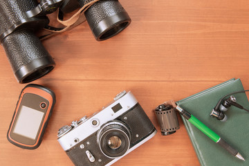 Old camera, reel with photographic film, notebook, binoculars, navigator lie on a wooden...