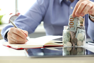 Male hand depositing some extra money in future needs closeup