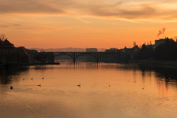 Fototapeta premium Old Bridge or Stari most in Maribor shot in the sunrise. Picture of the architectural landmark and popular attraction in Maribor with beautiful light in the background.