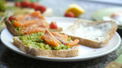 Cooking Toasts with avocado and smoked salmon on the white plate