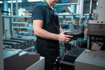 man working with automatic machinery on shoe factory