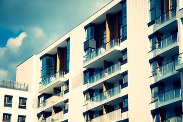 Exterior of new apartment buildings on a blue cloudy sky background. No people. Real estate business concept. Retro stylized colorful tonal filter effect.