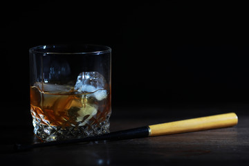 A glass of strong alcoholic drink with ice on a wooden bar counter. Whiskey with ice cubes. Glass...