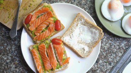 Cooking Toasts with avocado and smoked salmon on the white plate