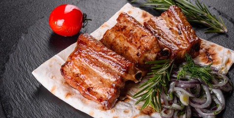 Fried ribs with rosemary, onion, sauce on a concrete background