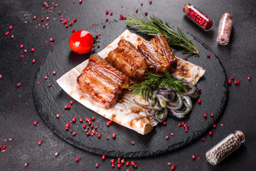 Fried ribs with rosemary, onion, sauce on a concrete background