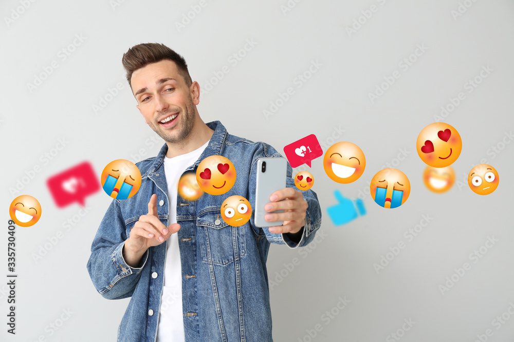 Wall mural handsome male blogger taking selfie on light background