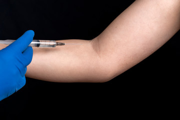 a doctor’s hand in disposable blue gloves is preparing to inject an medicine into a vein to a patient. development of a vaccine against coronavirus COVID-19 by scientists around the world.