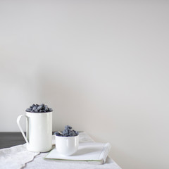 Two aluminum and porcelain cups with honeysuckle are on the table. Still life.