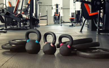 three black kettlebells with five black plates in the gym