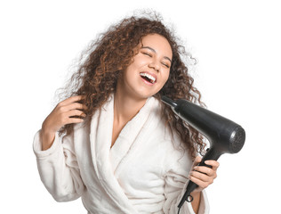 Beautiful young African-American woman with blow dryer on white background